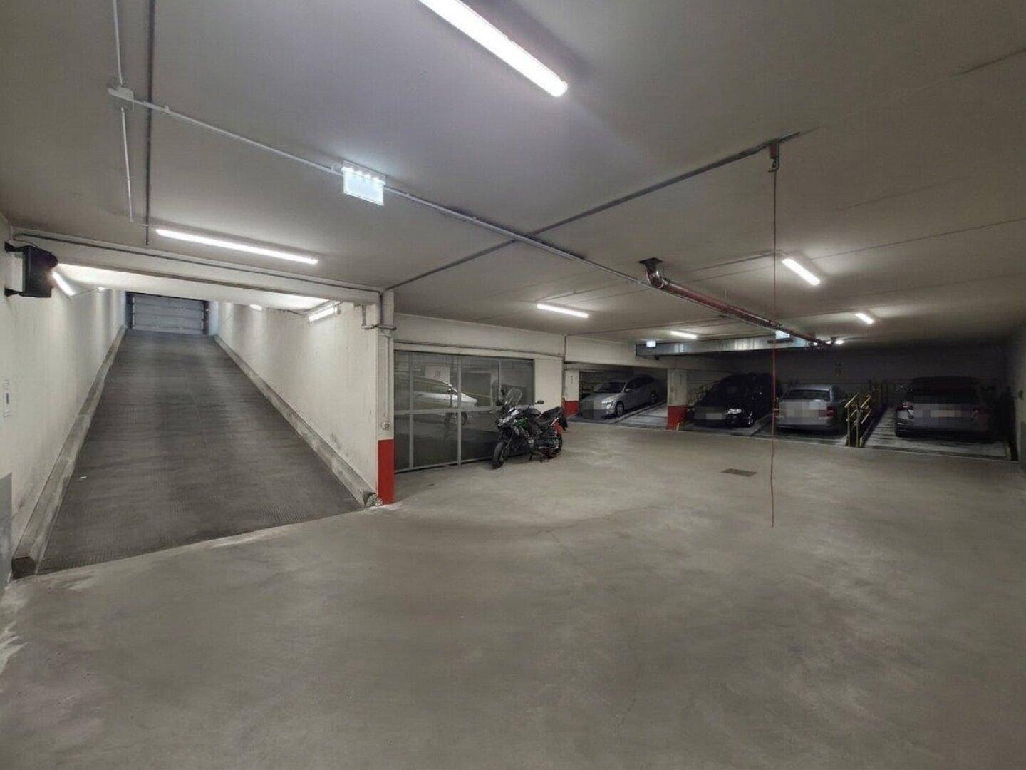 Einfahrt zur Tiefgarage mit Rampe und weiteren Parkplätzen im Untergeschoss.