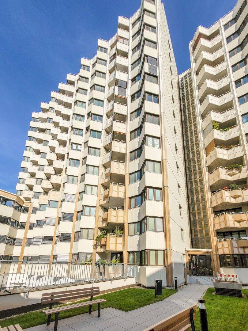 Hohes Apartmentgebäude mit vielen gestuften Balkonen unter blauem Himmel.