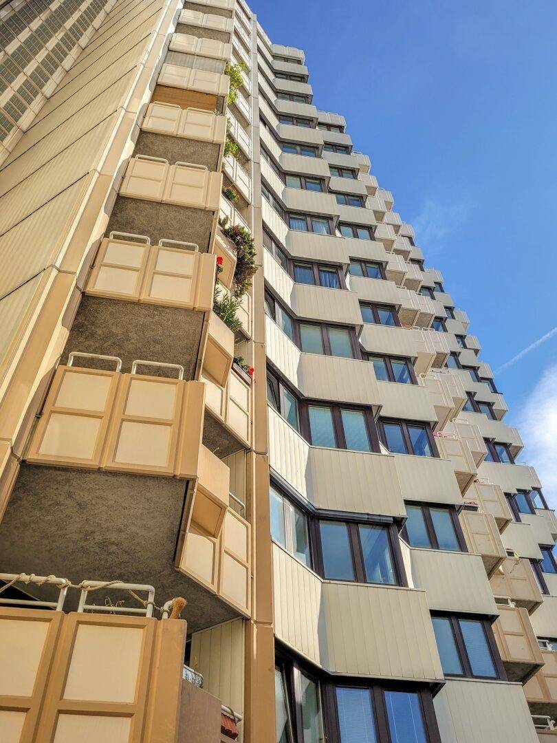 Detailansicht der Fassade eines modernen Apartmentgebäudes mit gestuften Balkonen und Fenstern.