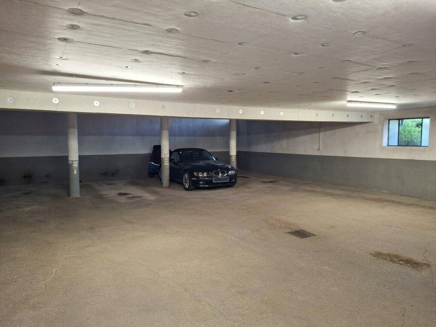Tiefgarage mit ausreichend Platz für Fahrzeuge und einfacher Beleuchtung.