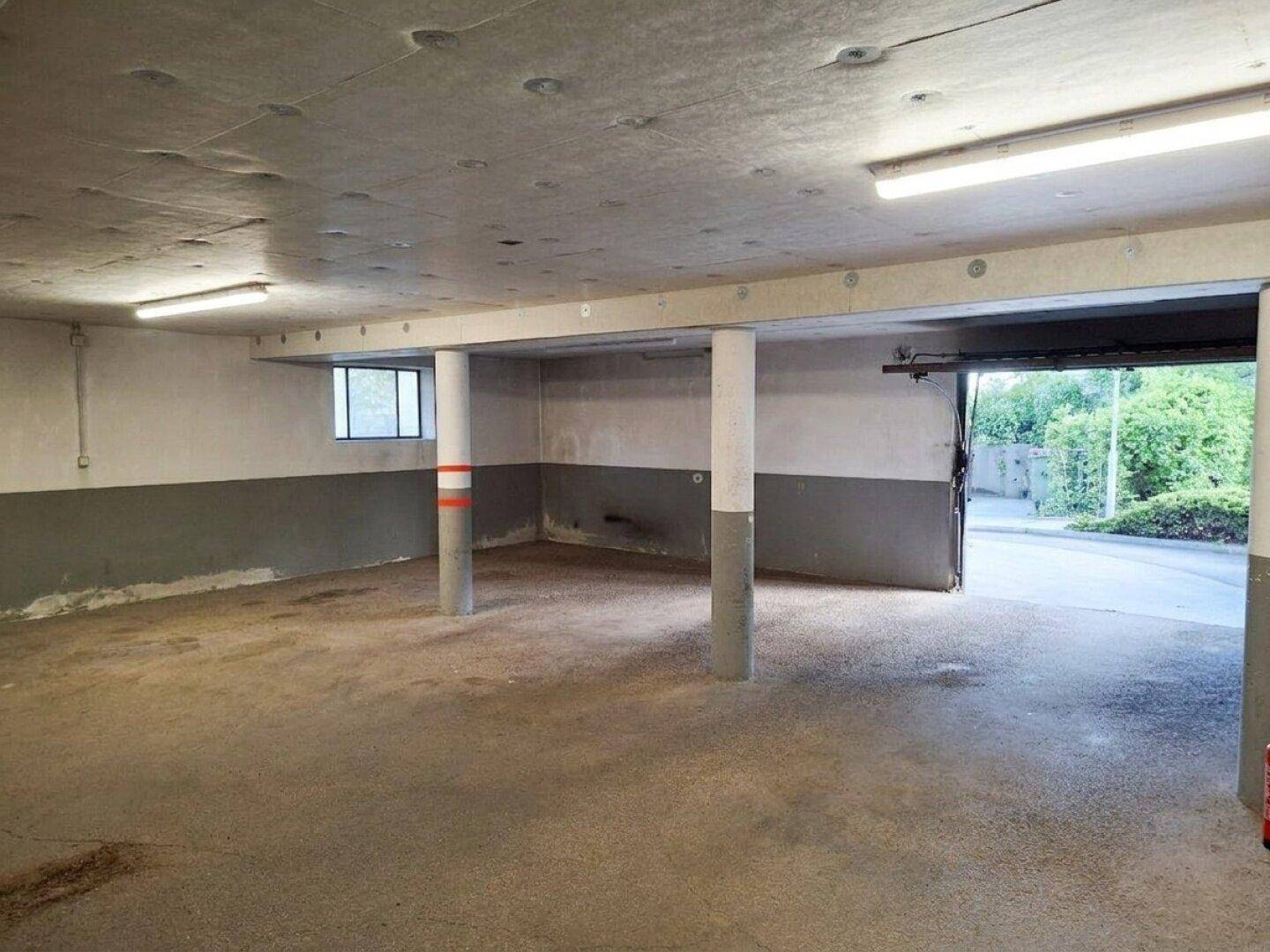 Geräumige Tiefgarage mit Zufahrt und Betonstützen, gut beleuchtet.