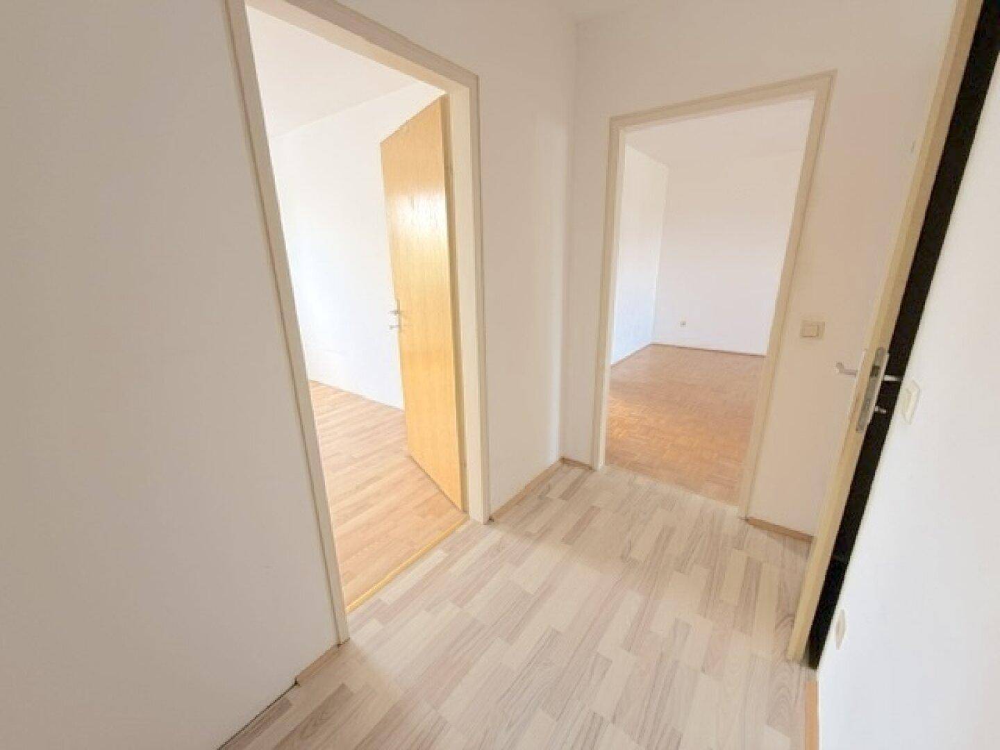 Heller Flur mit Laminatboden, der zu verschiedenen Zimmern der Wohnung führt.