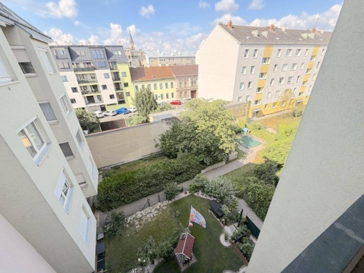Blick von oben auf einen gepflegten Gemeinschaftsgarten und die umliegenden Wohngebäude.