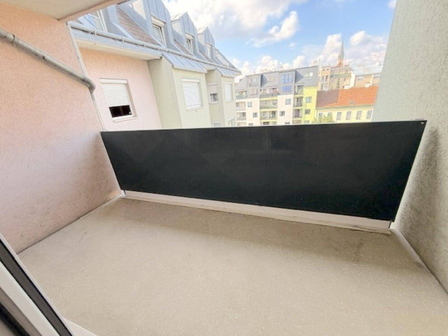 Unmöblierter Balkon mit Blick auf die umliegenden Gebäude und den Himmel.