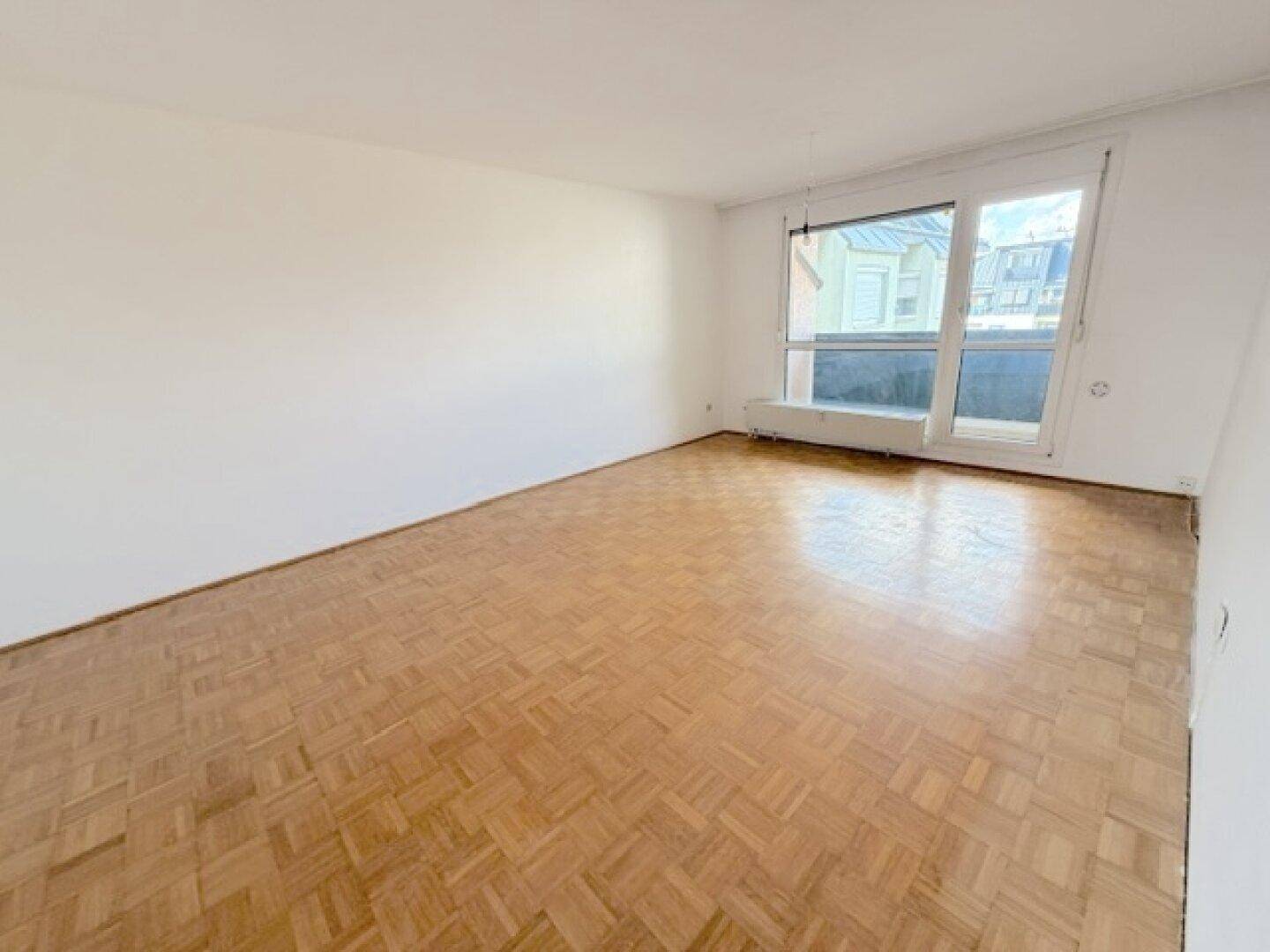 Helles Wohnzimmer mit Fischgrätparkett und Fensterfront, bereit zur individuellen Einrichtung.