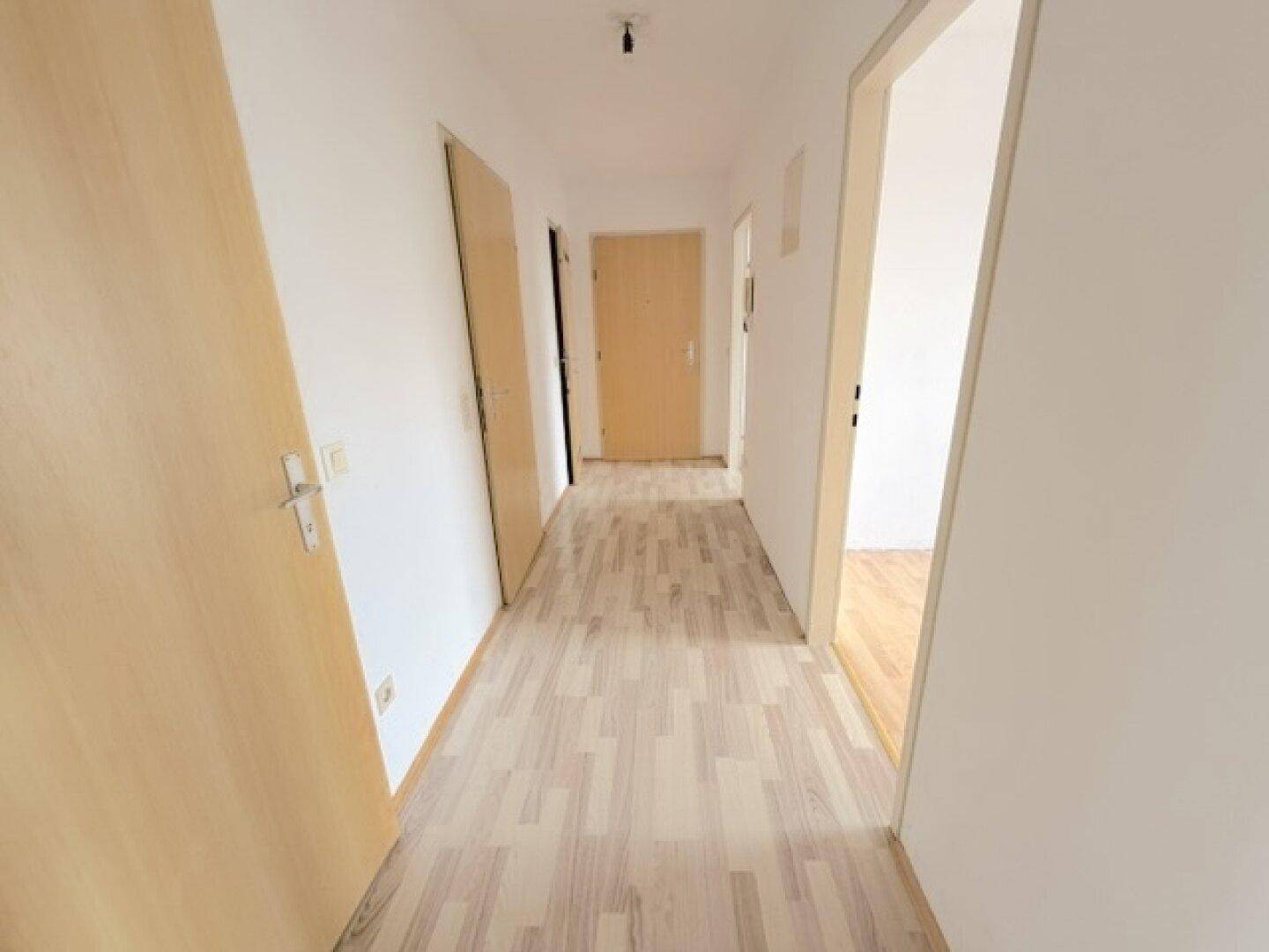 Langer, heller Flur mit Laminatboden und mehreren Türen zu den Wohnräumen.