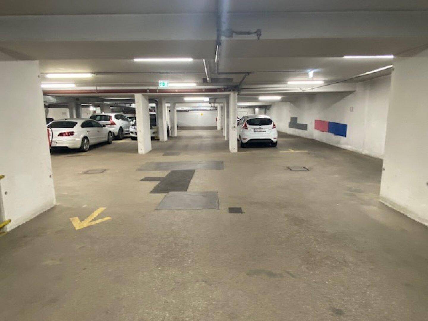 Geräumige Tiefgarage mit mehreren Stellplätzen und guter Beleuchtung für Fahrzeuge.