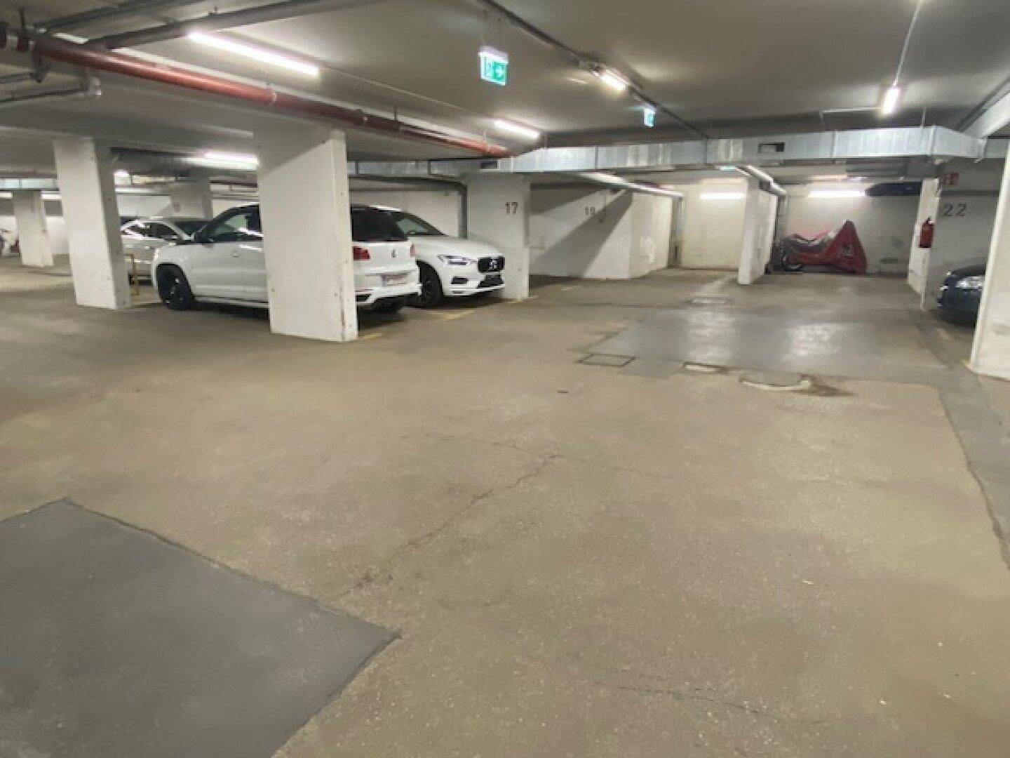 Übersichtliche Tiefgarage mit markierten Stellplätzen und geparkten Fahrzeugen im Untergeschoss.