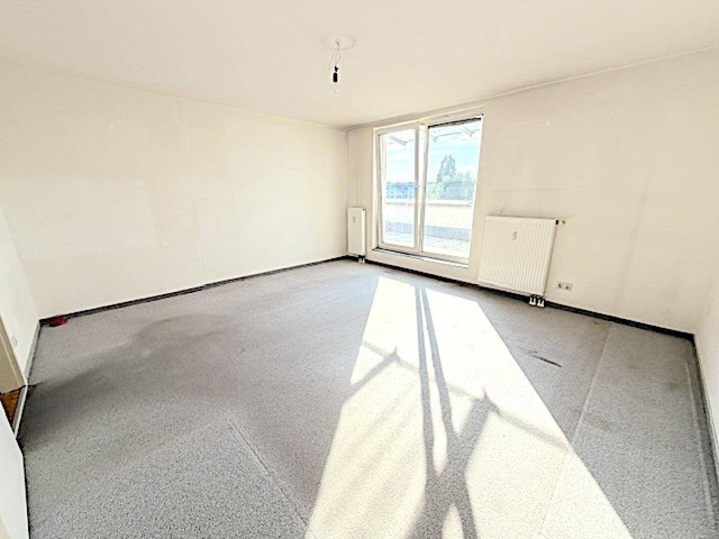 Lichtdurchflutetes Zimmer mit Teppichboden und Zugang zu einem sonnigen Außenbereich.