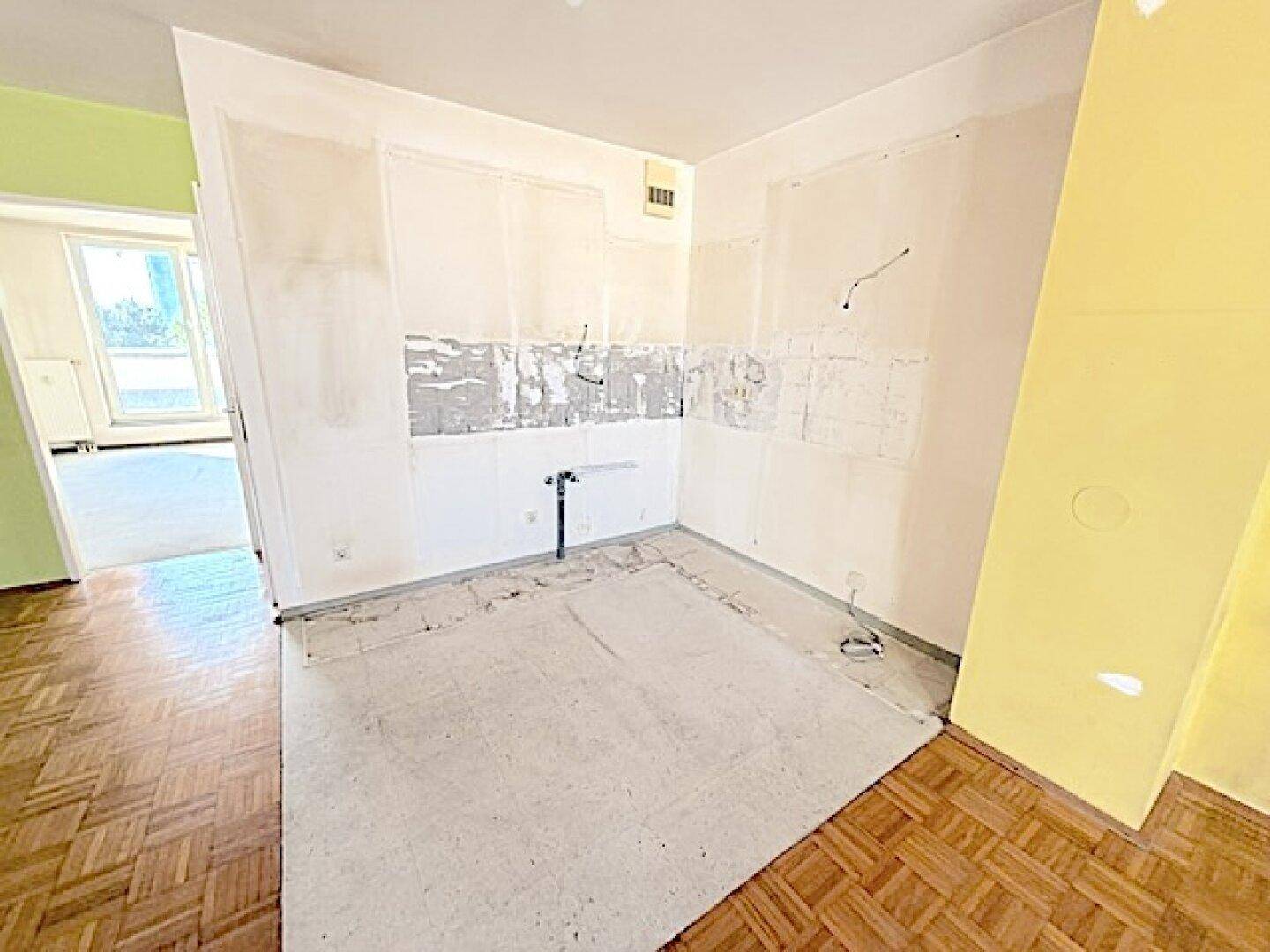 Vorbereiteter Küchenbereich mit freigelegten Wänden und Boden, bereit für die Installation.