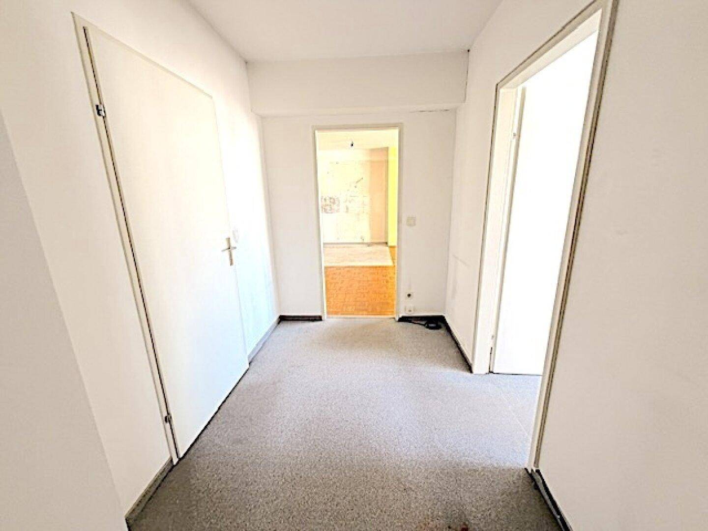 Heller Flur mit Teppichboden und mehreren Türen, die zu den angrenzenden Räumen führen.