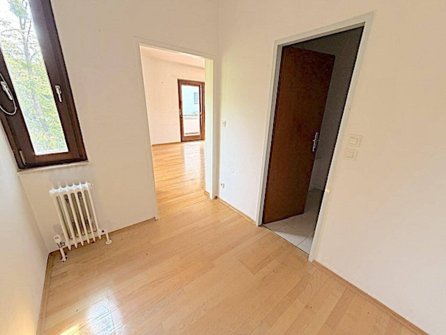 Heller Flur mit Parkettboden, der zu weiteren Zimmern und einem Fenster führt.