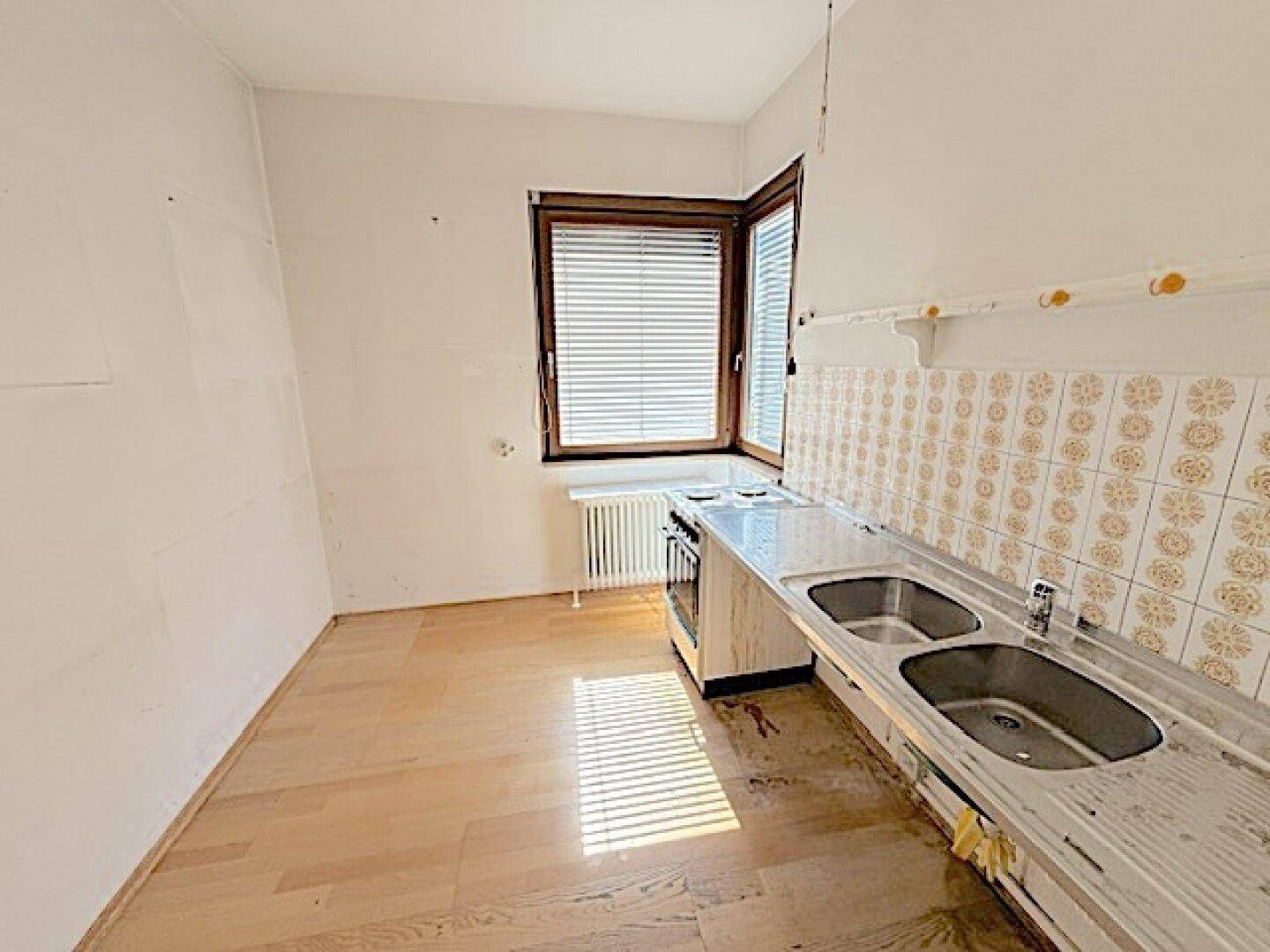 Küche mit Spülbecken, Herd und Fenster, bietet Potenzial für eine neue Gestaltung.