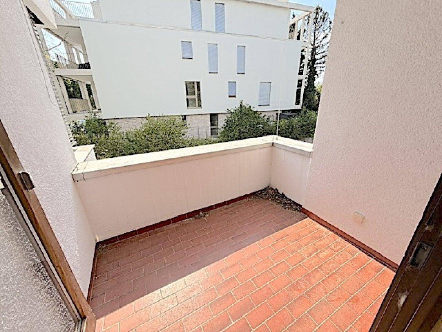 Balkon mit Terrakottafliesen und Blick auf die umliegenden Gebäude und Grünflächen.