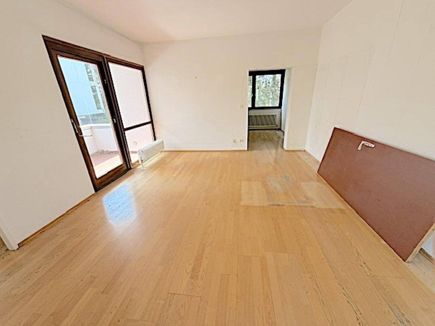 Geräumiges Zimmer mit Parkettboden und Balkonzugang, ideal für individuelle Gestaltung.