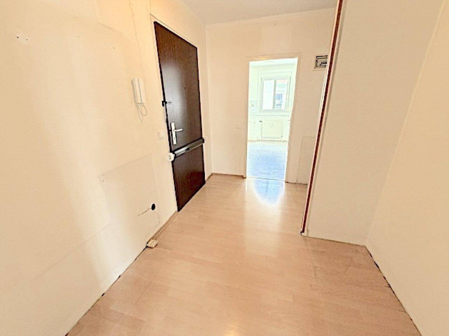 Heller Eingangsbereich mit Sicherheitstür und Blick in angrenzende Räume.