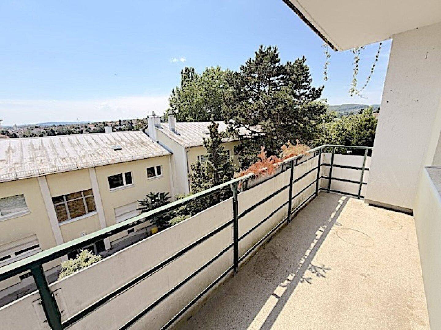 Balkon mit weitem Blick über die Dächer und grüne Landschaft.