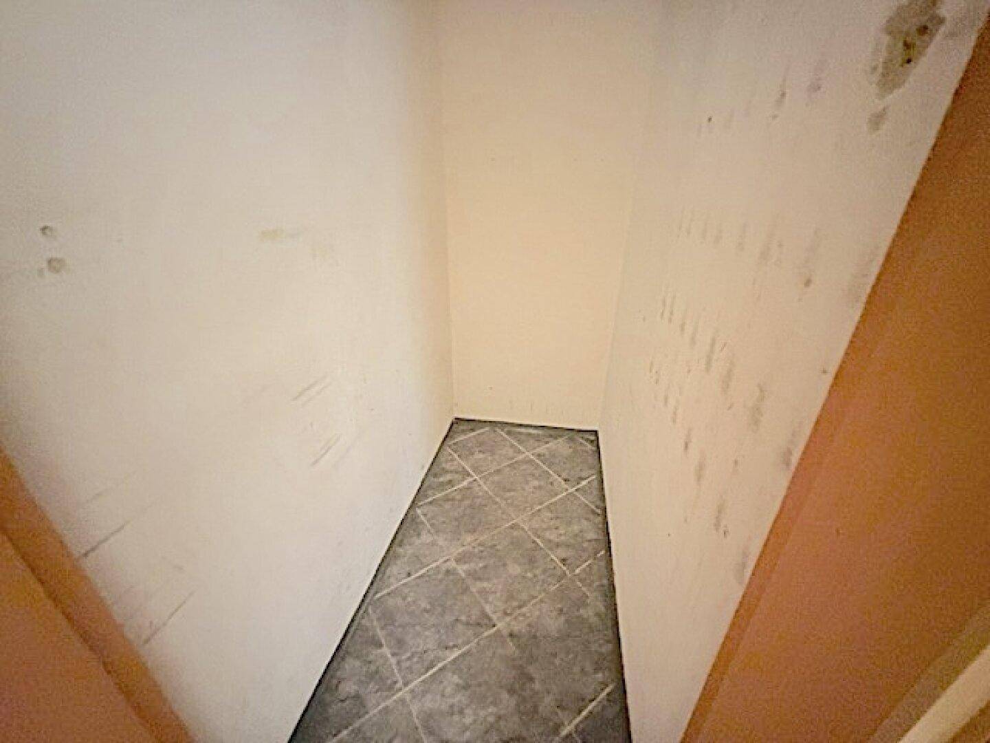 Kleiner Abstellraum mit Fliesenboden und hellen Wänden.