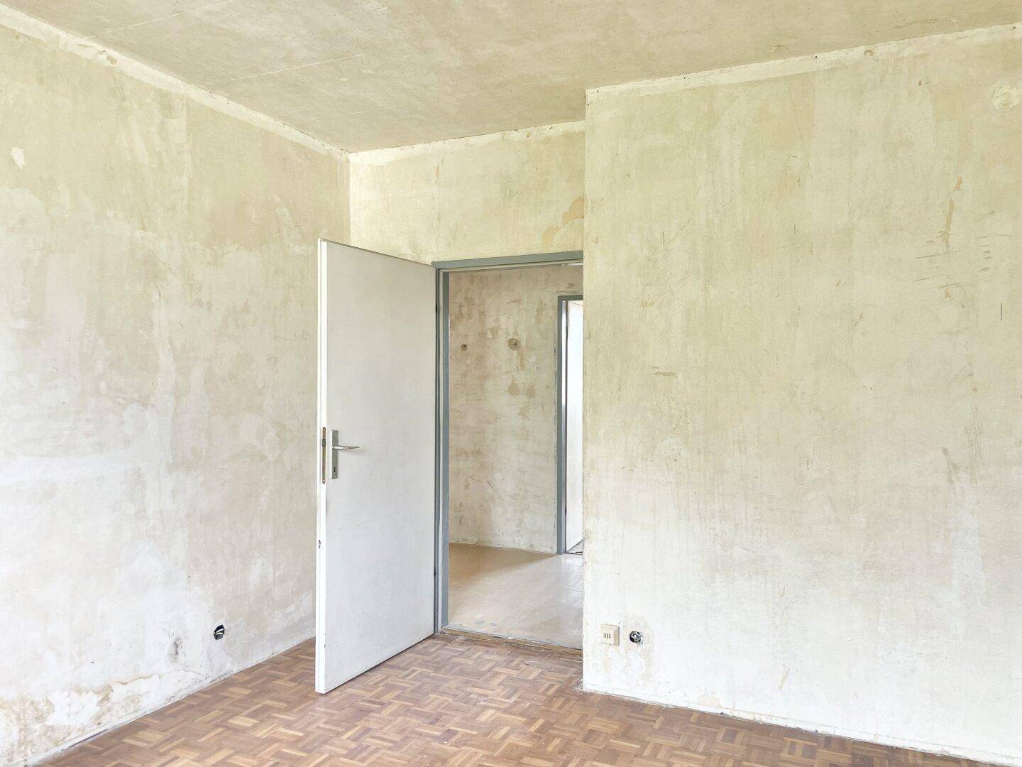 Zimmer mit Parkettboden und offener Tür, bietet viel Potenzial für eine moderne Gestaltung.