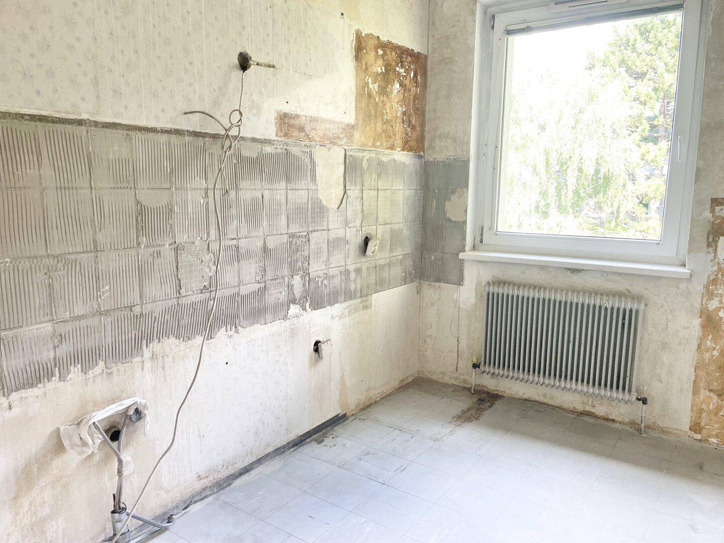 Unfertige Küche mit vorbereiteten Wänden für Fliesen und einem Fenster für Tageslicht.
