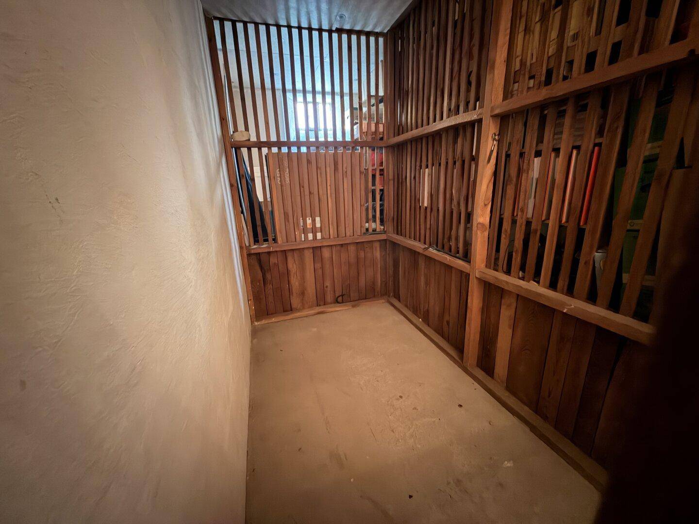 Lagerraum im Keller mit Holzwänden und Betonboden, ideal für zusätzlichen Stauraum im Untergeschoss.