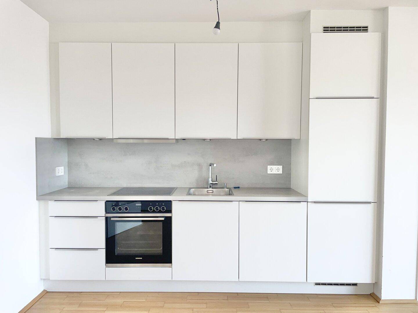 Moderne Einbauküche in Weiß mit Induktionskochfeld, Backofen und integrierter Spüle.