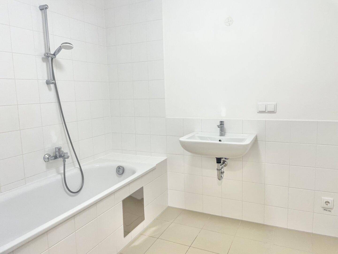 Modernes Badezimmer mit weiß gefliesten Wänden, Badewanne und Waschbecken.