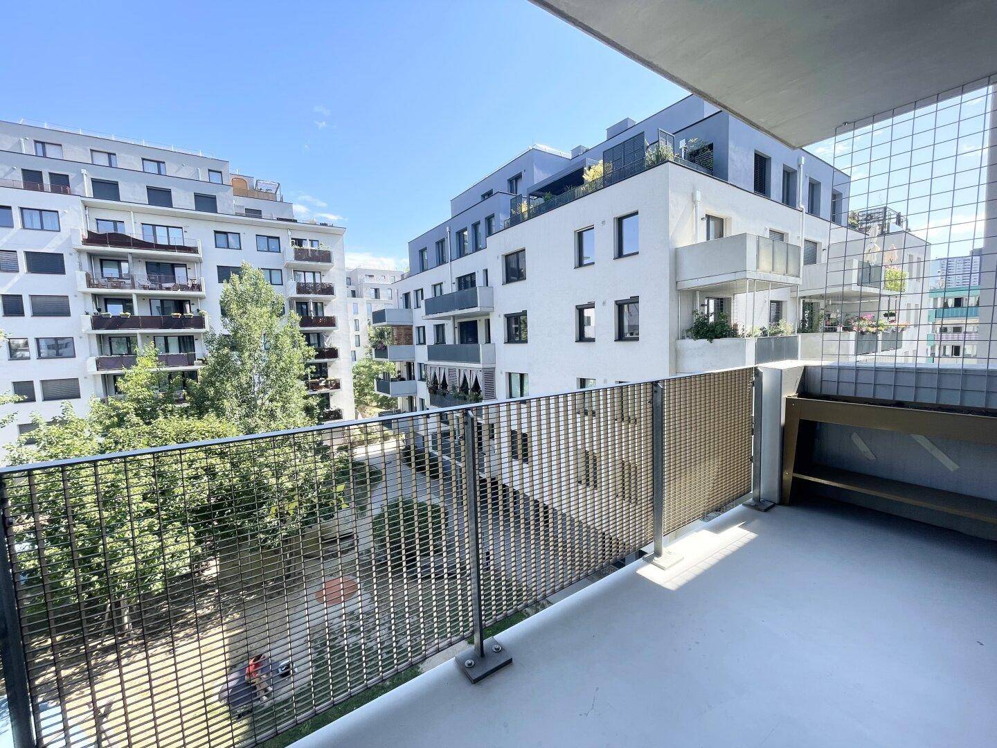 Leerer Balkon mit Metallgeländer und Ausblick auf die umliegenden Wohngebäude.