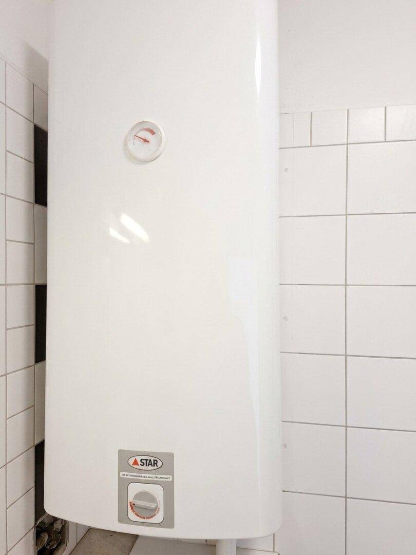 Nahaufnahme des Warmwasserboilers im Badezimmer mit Temperaturanzeige.