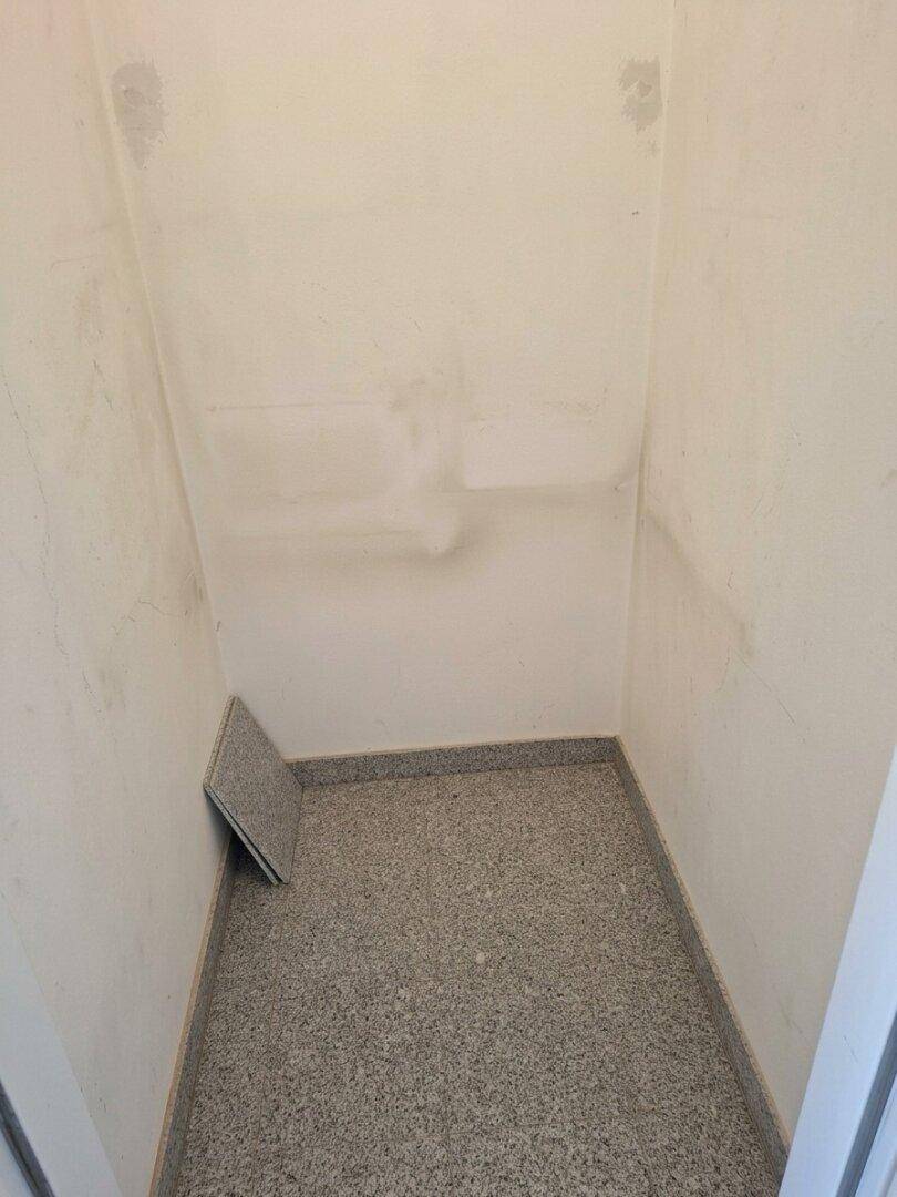 Kleiner Abstellraum mit hellen Wänden und grauem Fliesenboden.
