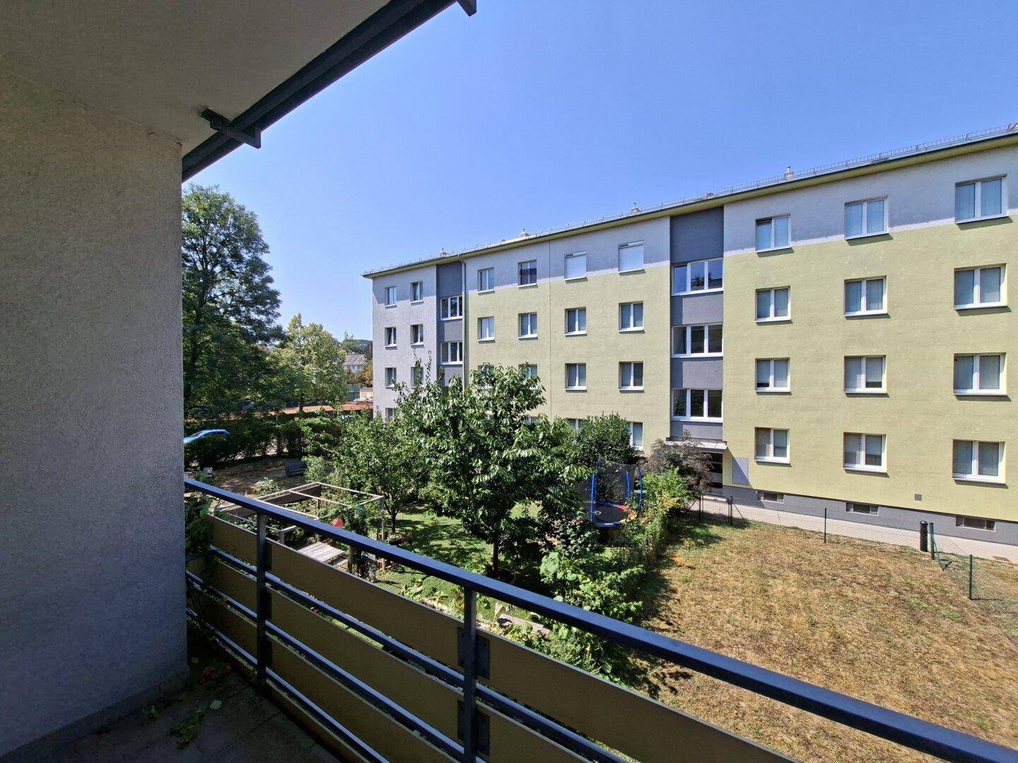 Balkon mit Blick auf den begrünten Innenhof und die Fassade des Nachbargebäudes.