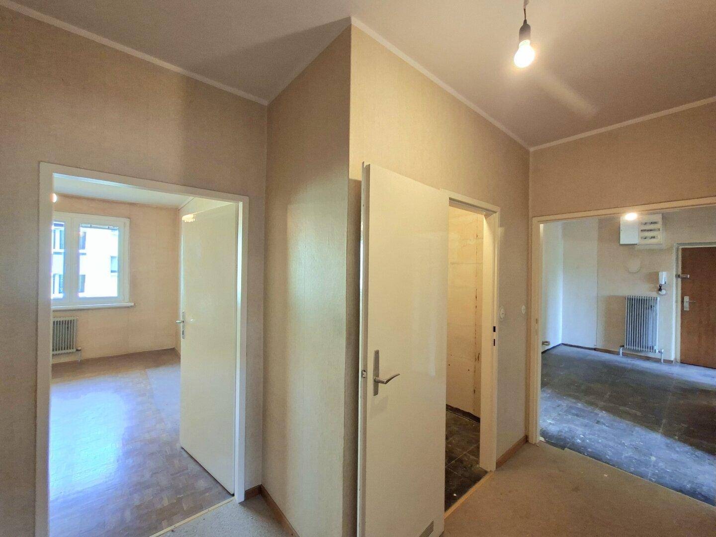 Flur mit Fliesenboden und offenen Türen, die den Blick in angrenzende Räume freigeben.