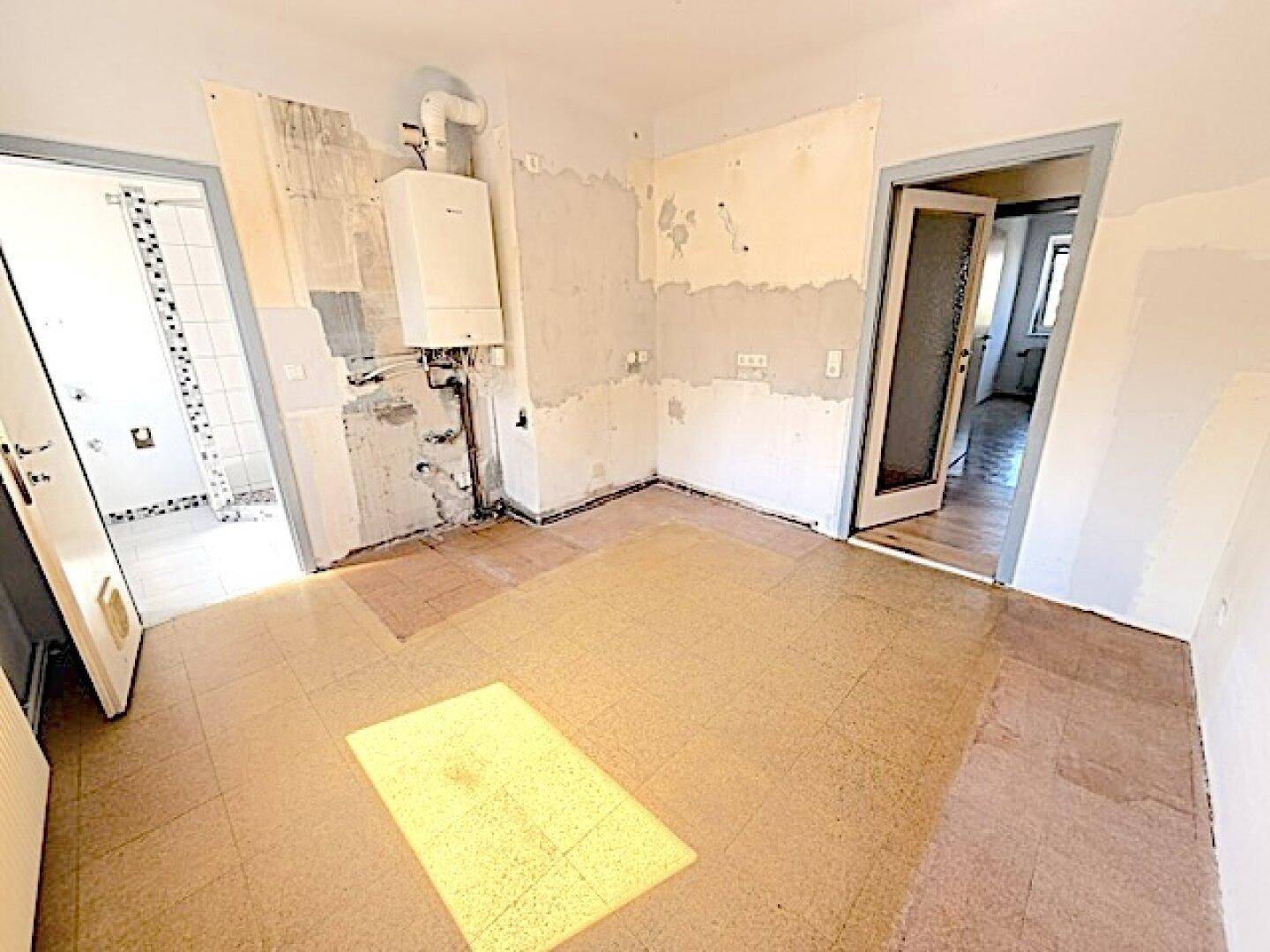 Renovierungsbedürftige Küche mit Boiler und freigelegten Wänden, ideal für eine moderne Neugestaltung.