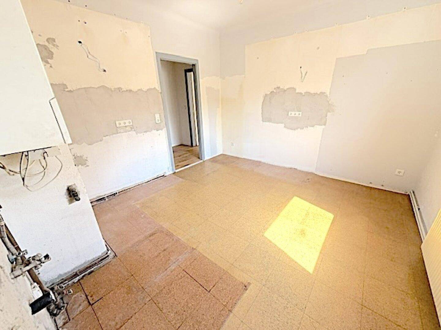 Renovierungsbedürftige Küche mit freigelegten Wänden und alten Fliesen, bereit für eine Neugestaltung.