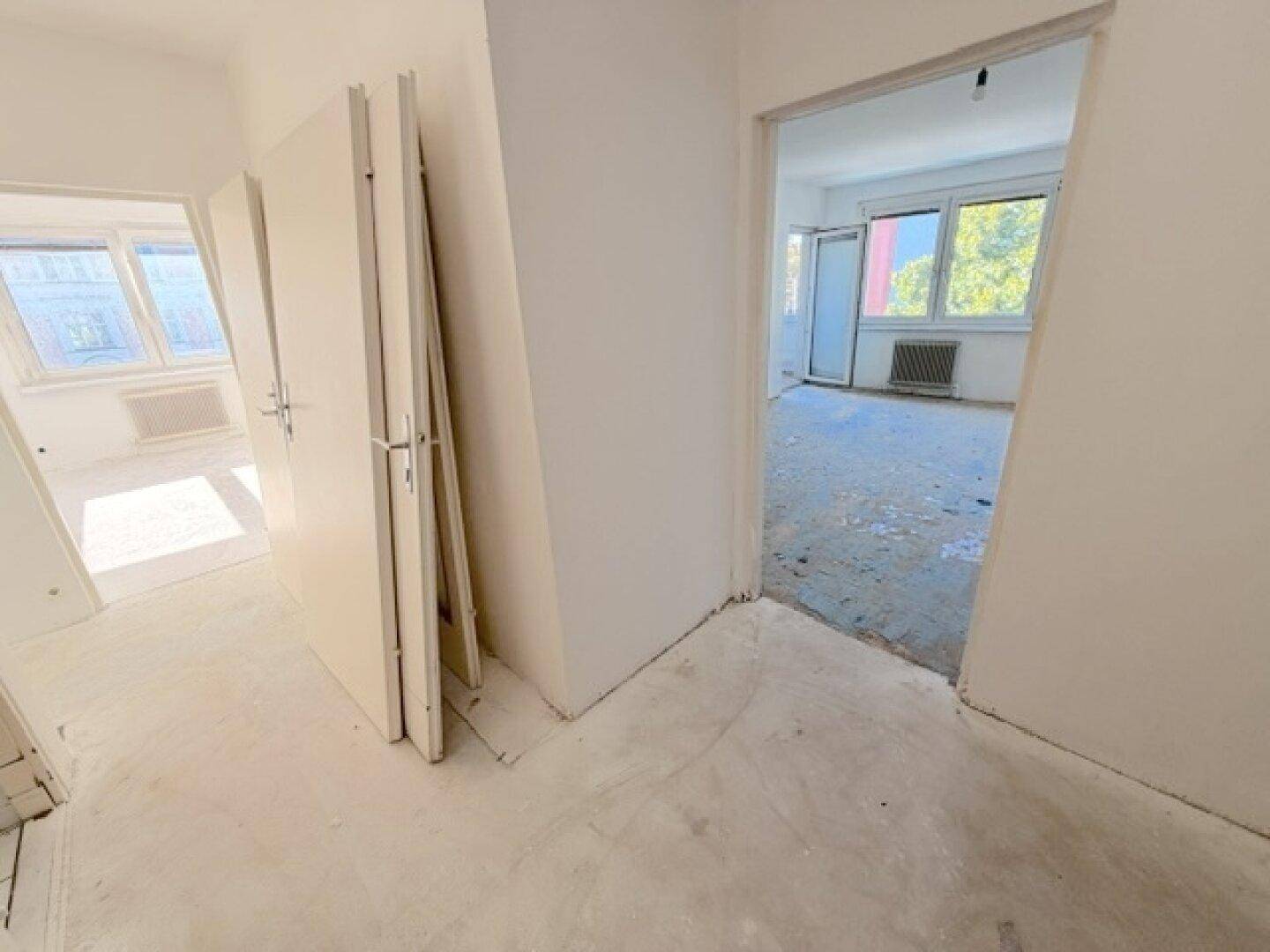 Heller Flur mit weißen Wänden und Zugang zu mehreren Zimmern der Wohnung.