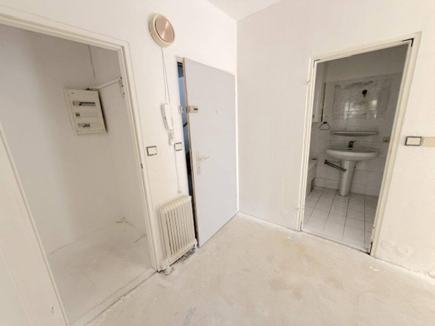 Flur mit Zugang zu einem Badezimmer und einem Abstellraum, ausgestattet mit einem Heizkörper.
