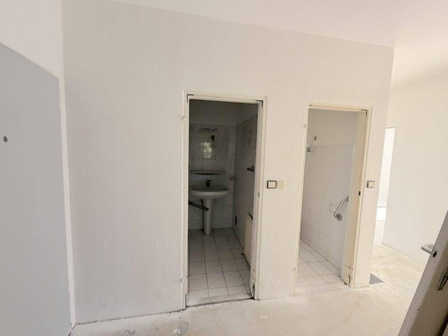 Flur mit Zugang zu einem Badezimmer und einem separaten WC, beide mit Fliesenböden.