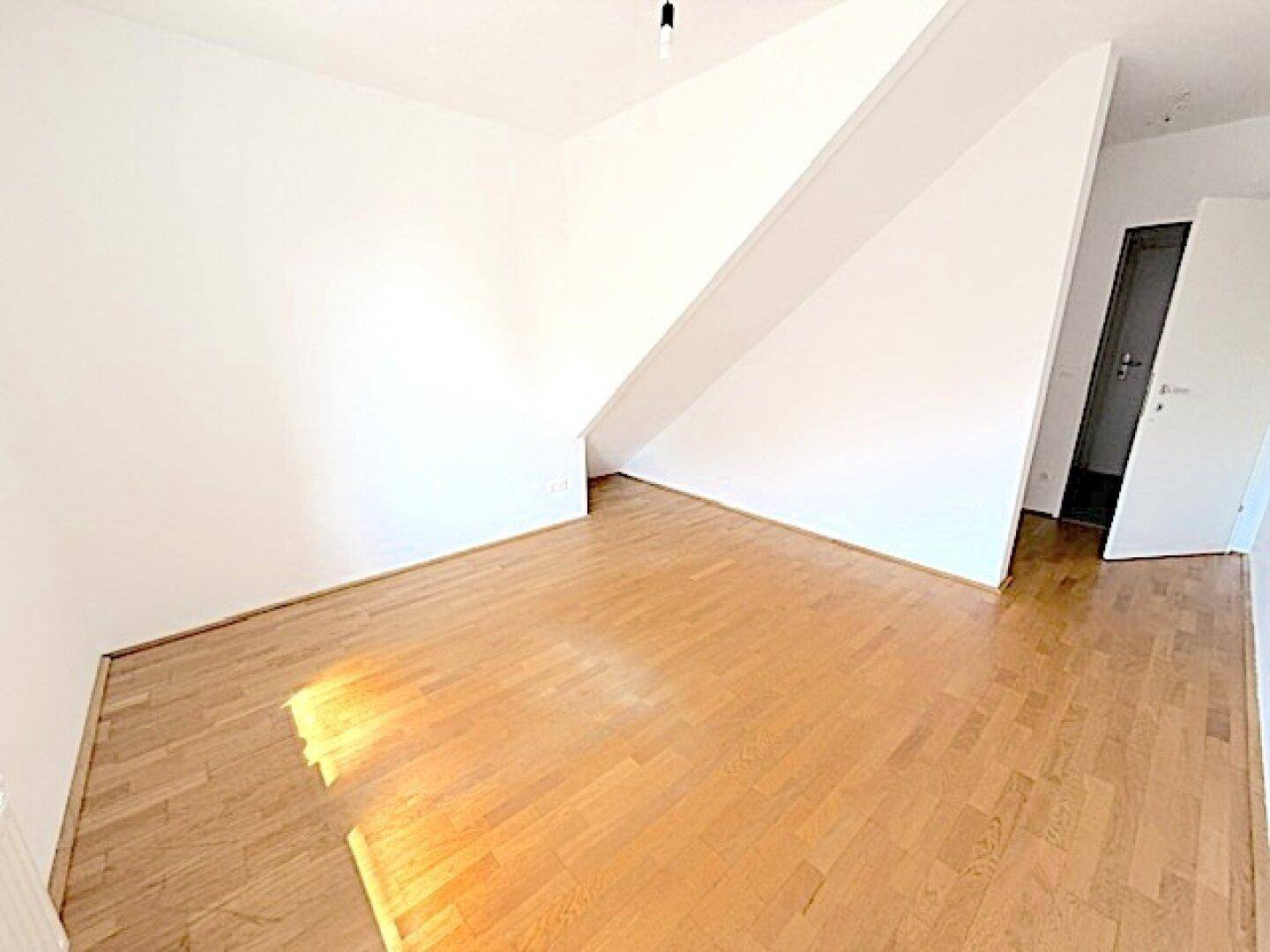 Geräumiges Zimmer mit Holzboden und weiß gestrichenen Wänden, bereit zur individuellen Gestaltung.