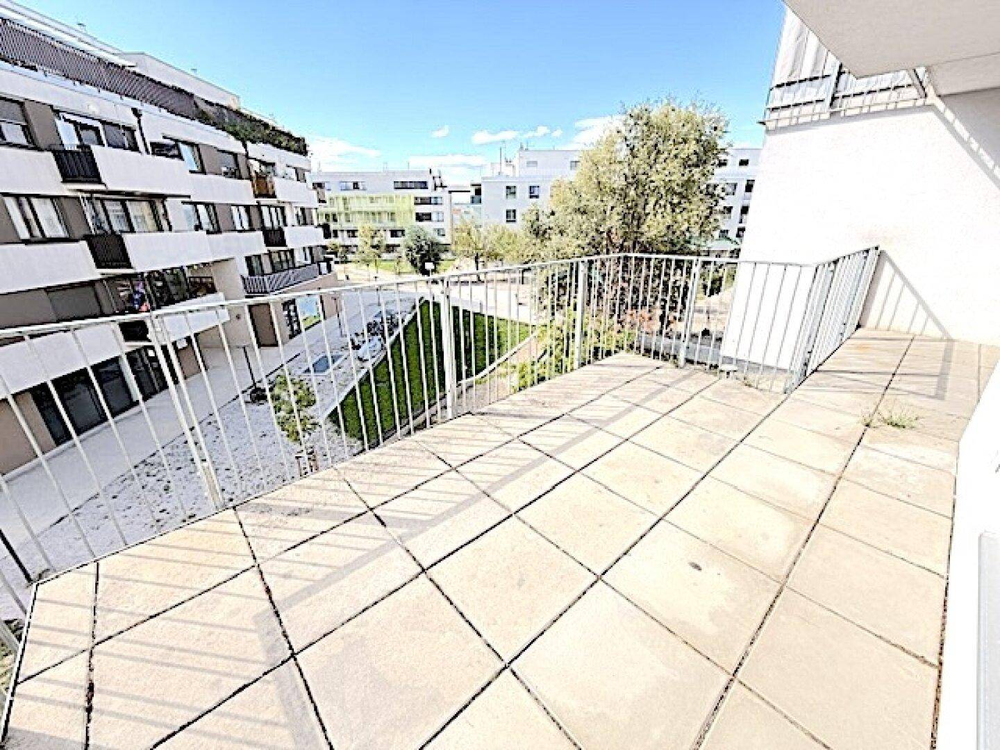 Geräumiger Balkon mit Fliesenboden und Blick auf die umliegende Wohnbebauung.