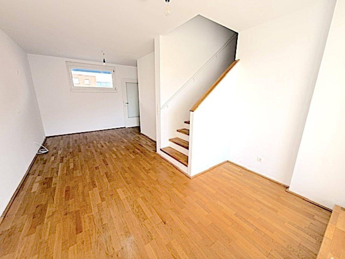 Geräumiger Wohnbereich mit Holzboden und Treppe, bereit für individuelle Einrichtungsideen.