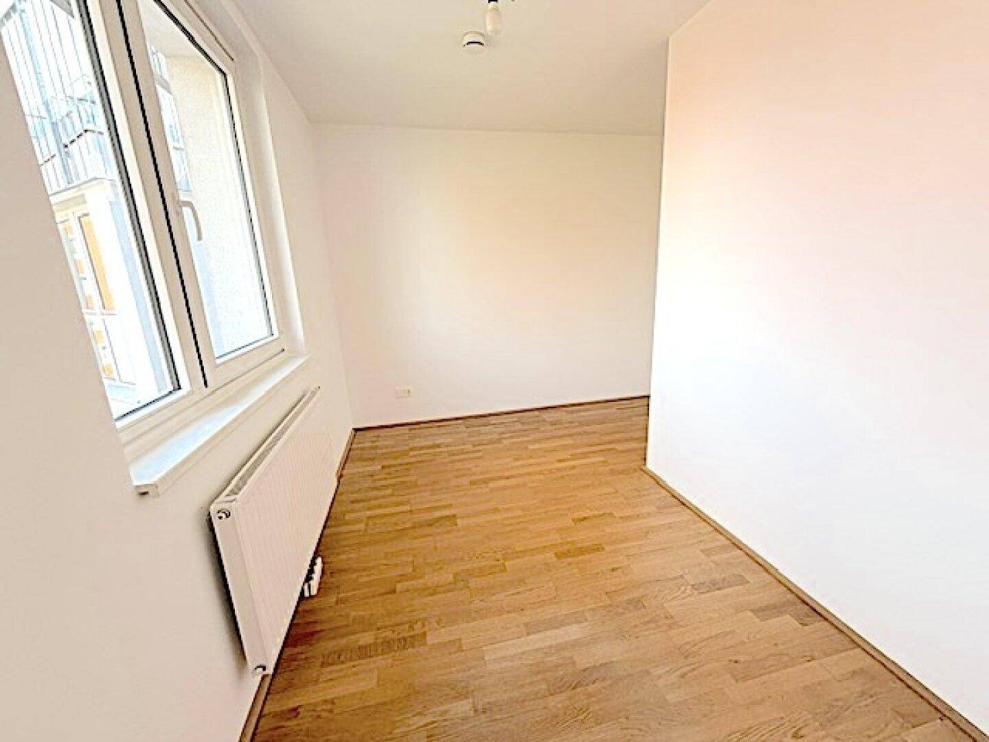 Helles Zimmer mit Holzboden und Blick nach draußen, ideal für ein ruhiges Schlafzimmer.