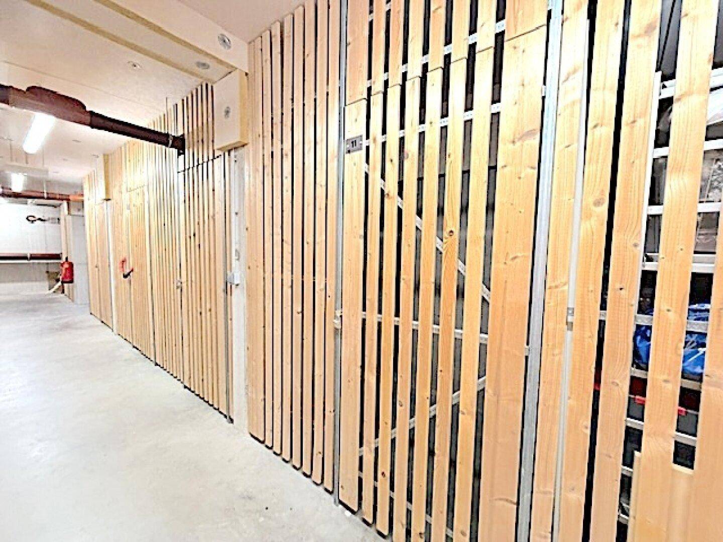 Reihe von Holzverschlägen in einem Kellerabteil, ideal für zusätzlichen Stauraum.