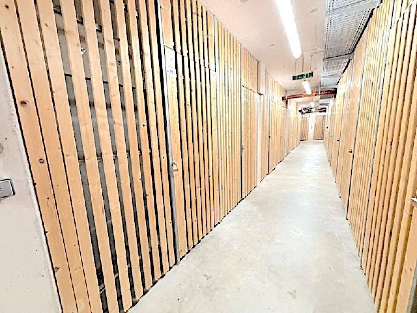 Langer Gang mit zahlreichen Holzverschlägen, die als Kellerabteile dienen.