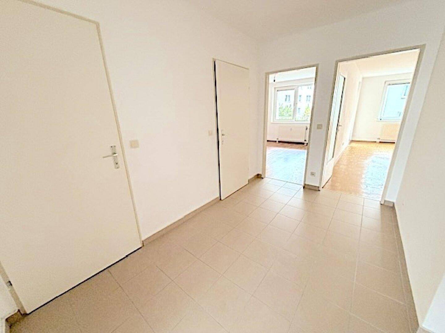 Heller Flur mit Fliesenboden und Zugang zu mehreren Zimmern der Wohnung.