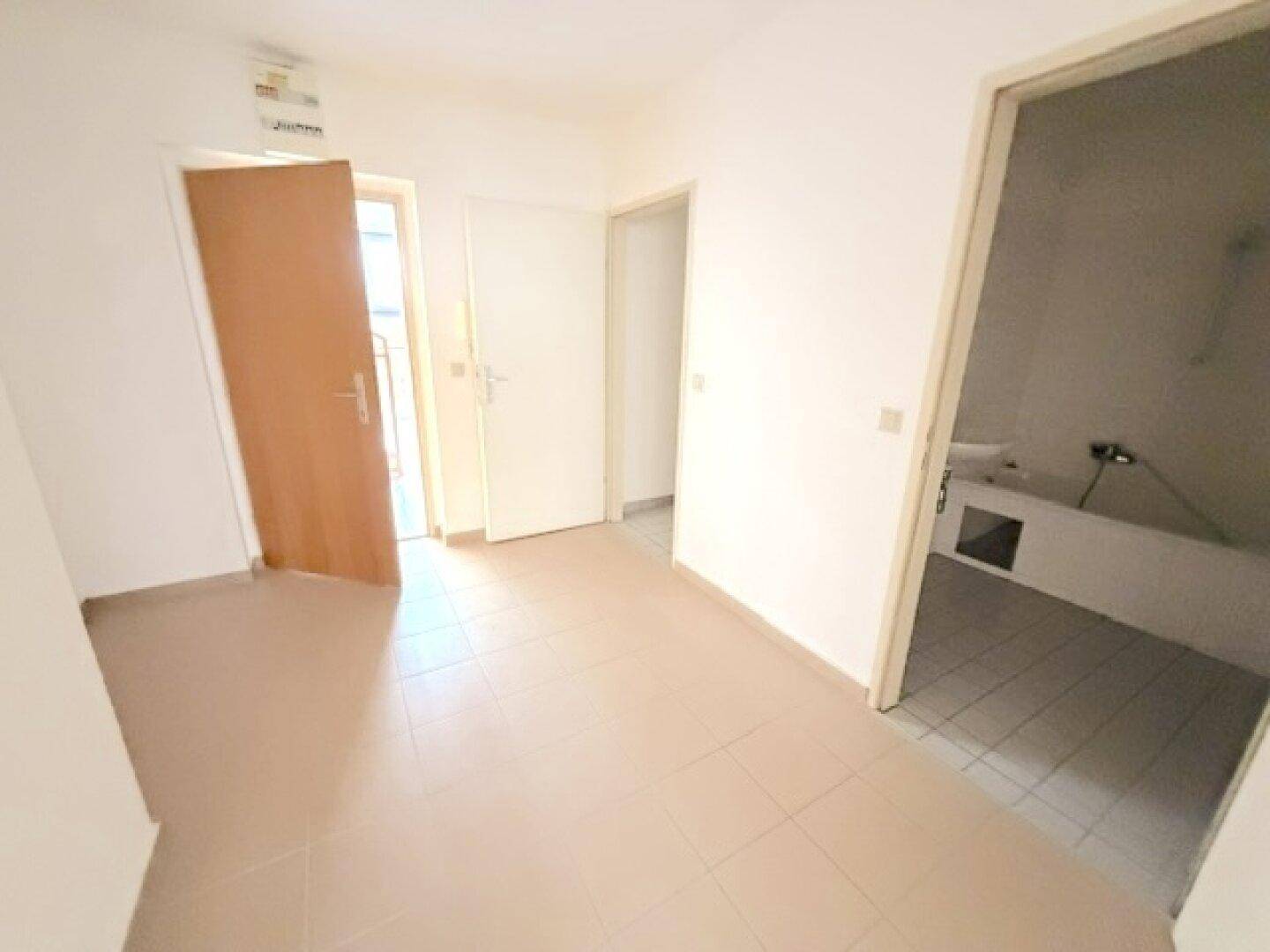 Flur mit Fliesenboden und Zugang zum Badezimmer und weiteren Räumen.