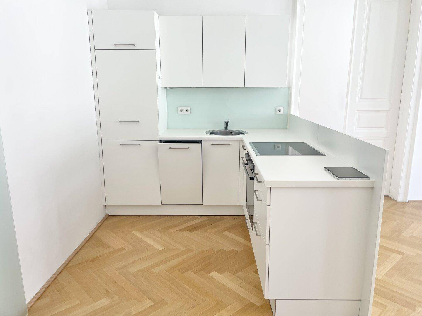 Detaillierte Ansicht der modernen weißen Küchenzeile mit integrierten Geräten und Spülbecken.