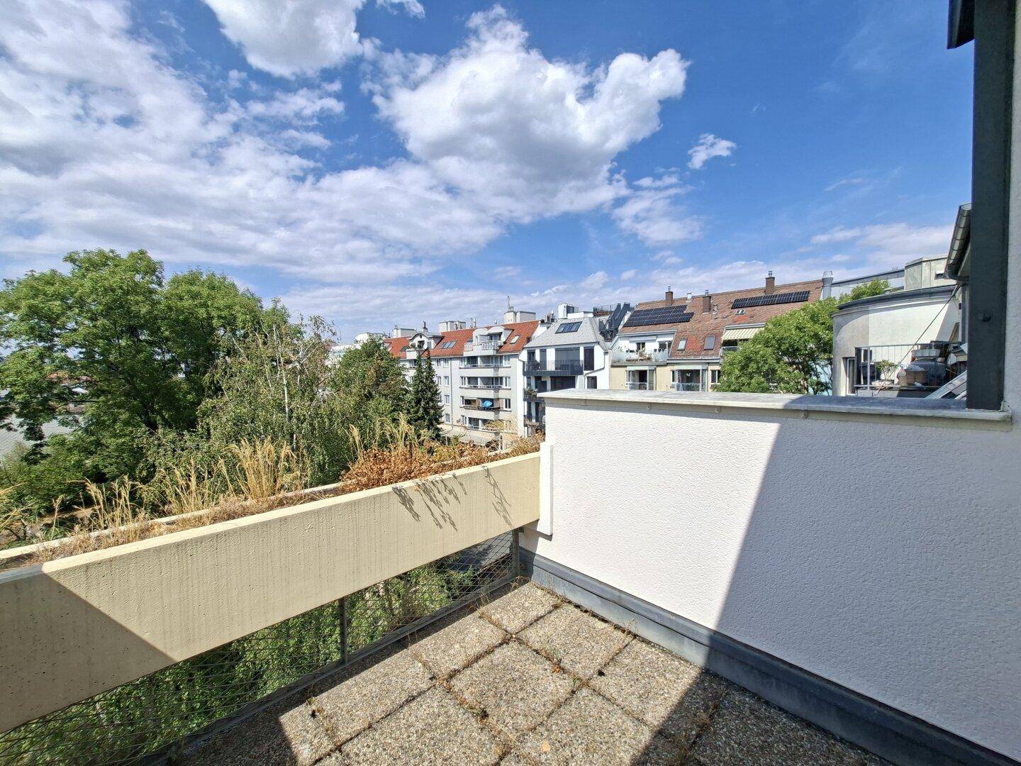 Geräumiger Balkon mit Blick auf die umliegenden Gebäude und viel Grün.