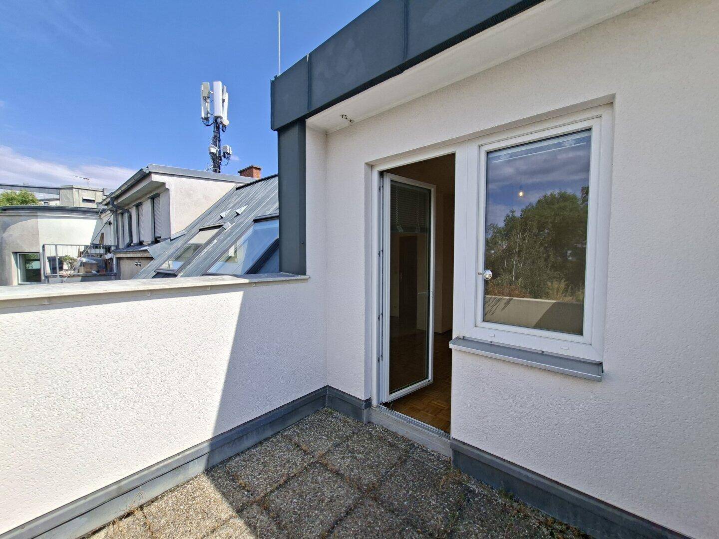 Kleiner Balkon mit Zugang zum Innenbereich und Blick über die Dächer der Stadt.