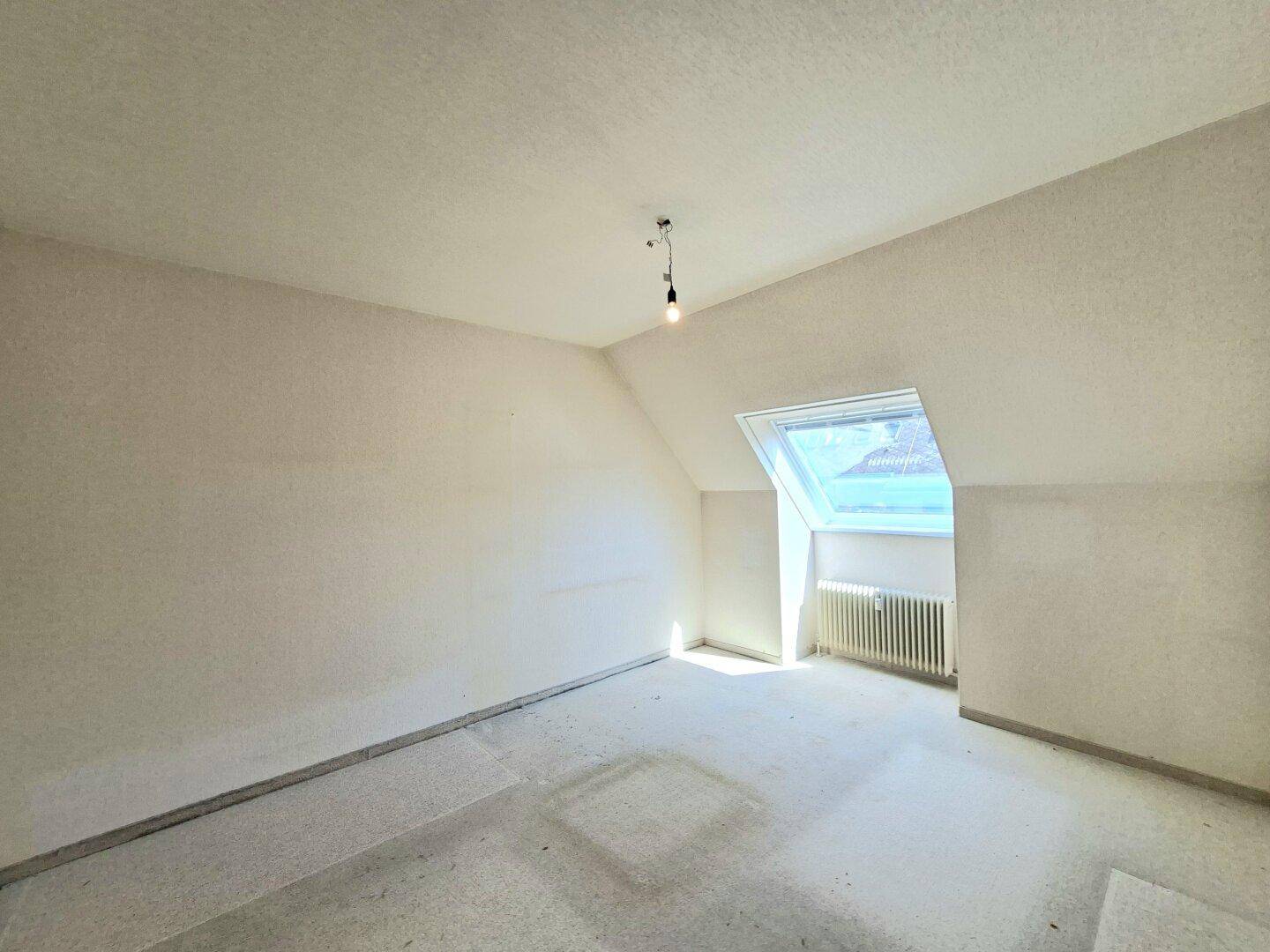 Lichtdurchflutetes Schlafzimmer mit Dachschräge, Dachfenster und vorbereitetem Boden.
