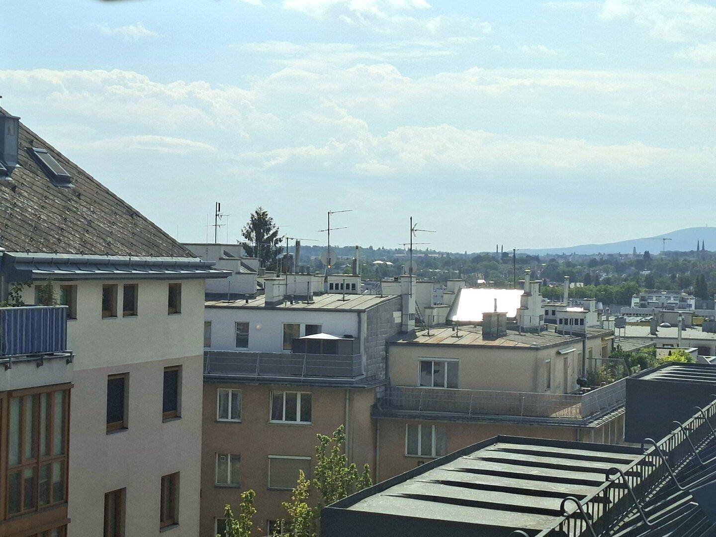 Weitläufiger Blick über die Stadtlandschaft mit Bergen am Horizont.